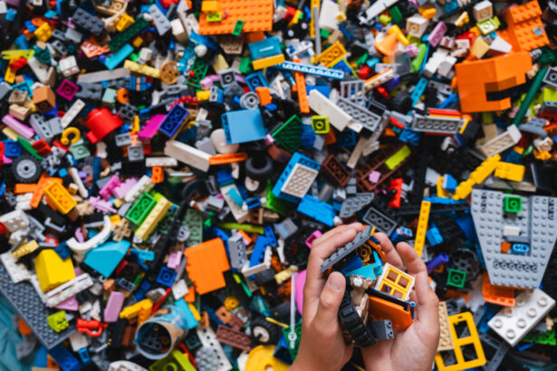 Huge pile of mixed colorful plastic bricks toys with children's hands. Small plastic building blocks in multiple colours, top view, lifestyle photo. Kids leisure, children education and development.